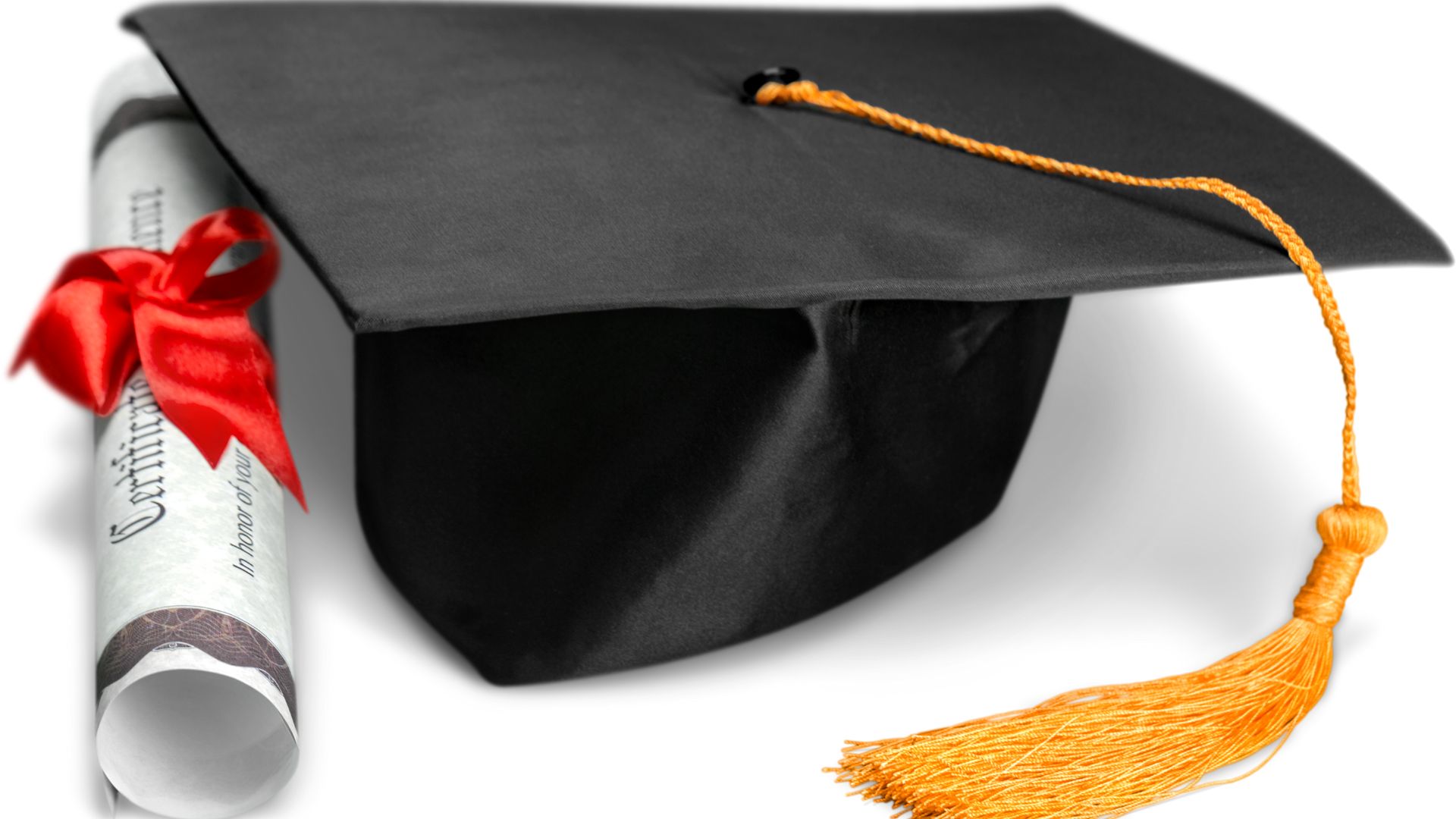 rolled up diploma in red ribbon next to graduate cap and gown