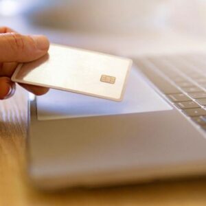 holding credit card next to a laptop