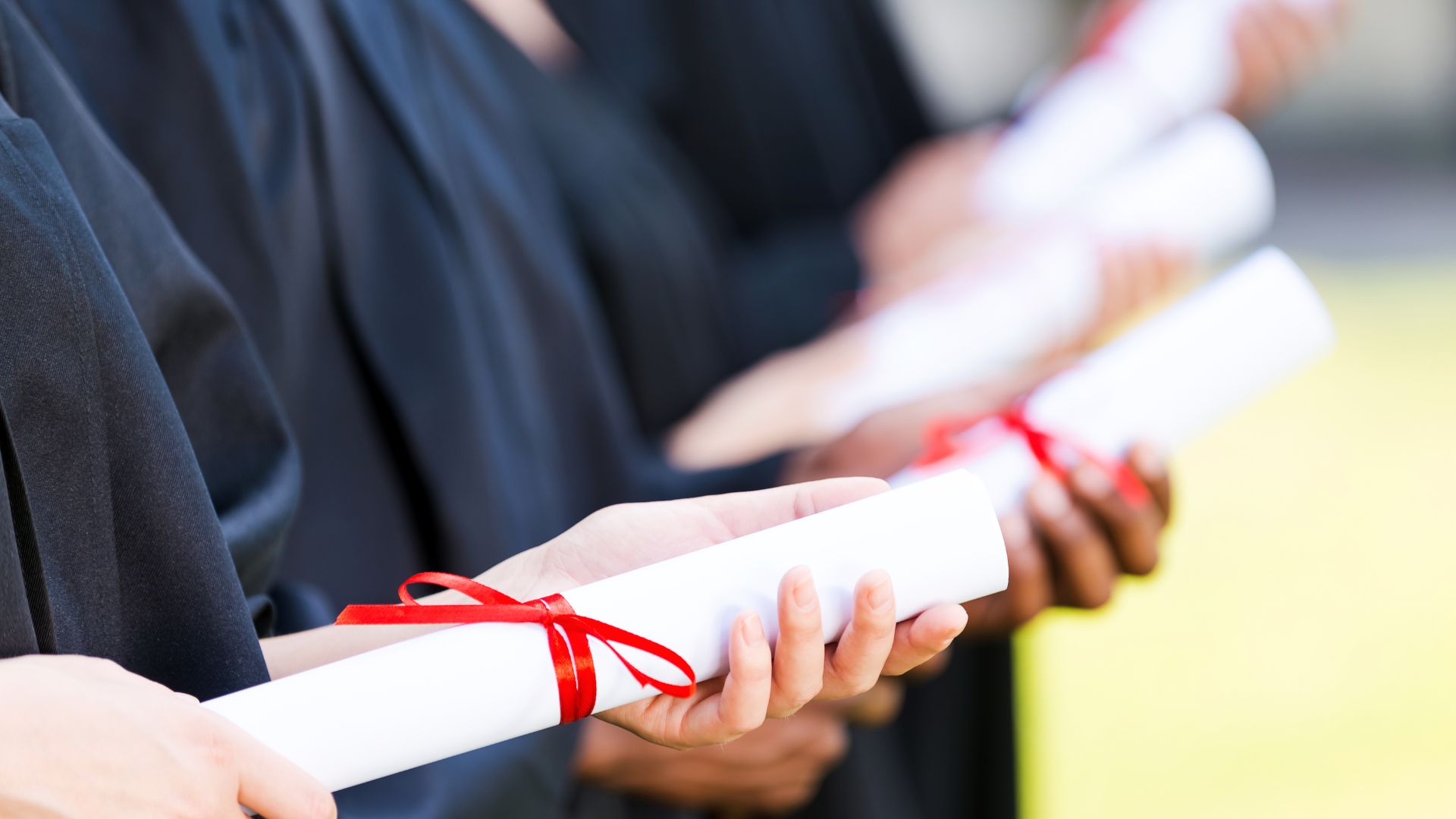 Key Points to Consider Before Buying A Canada Replacement Degree! 2 graduates holding diplomas tied up in red ribbon